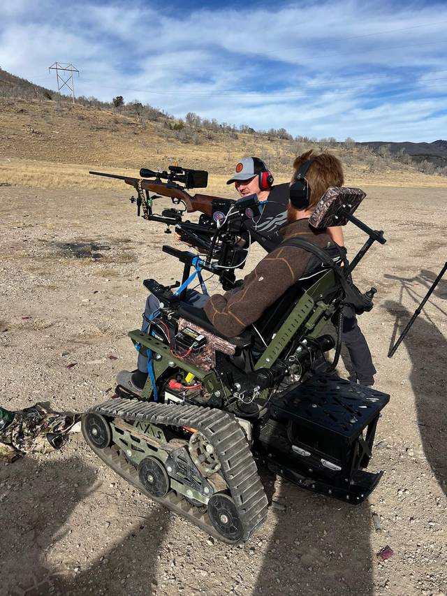 Participant in a tracked wheelchair lining up a shot with an instructor's help.